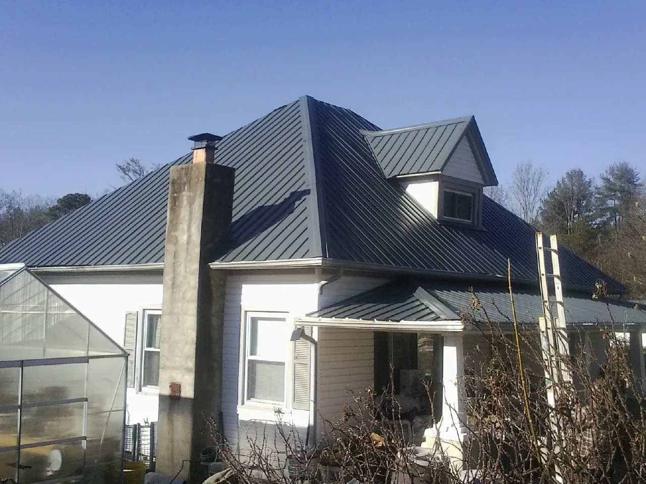 Dark blue standing seam metal roof on a white farmhouse with dormer — Slate & Tile Roof Repair by Roofing Brothers in Orange