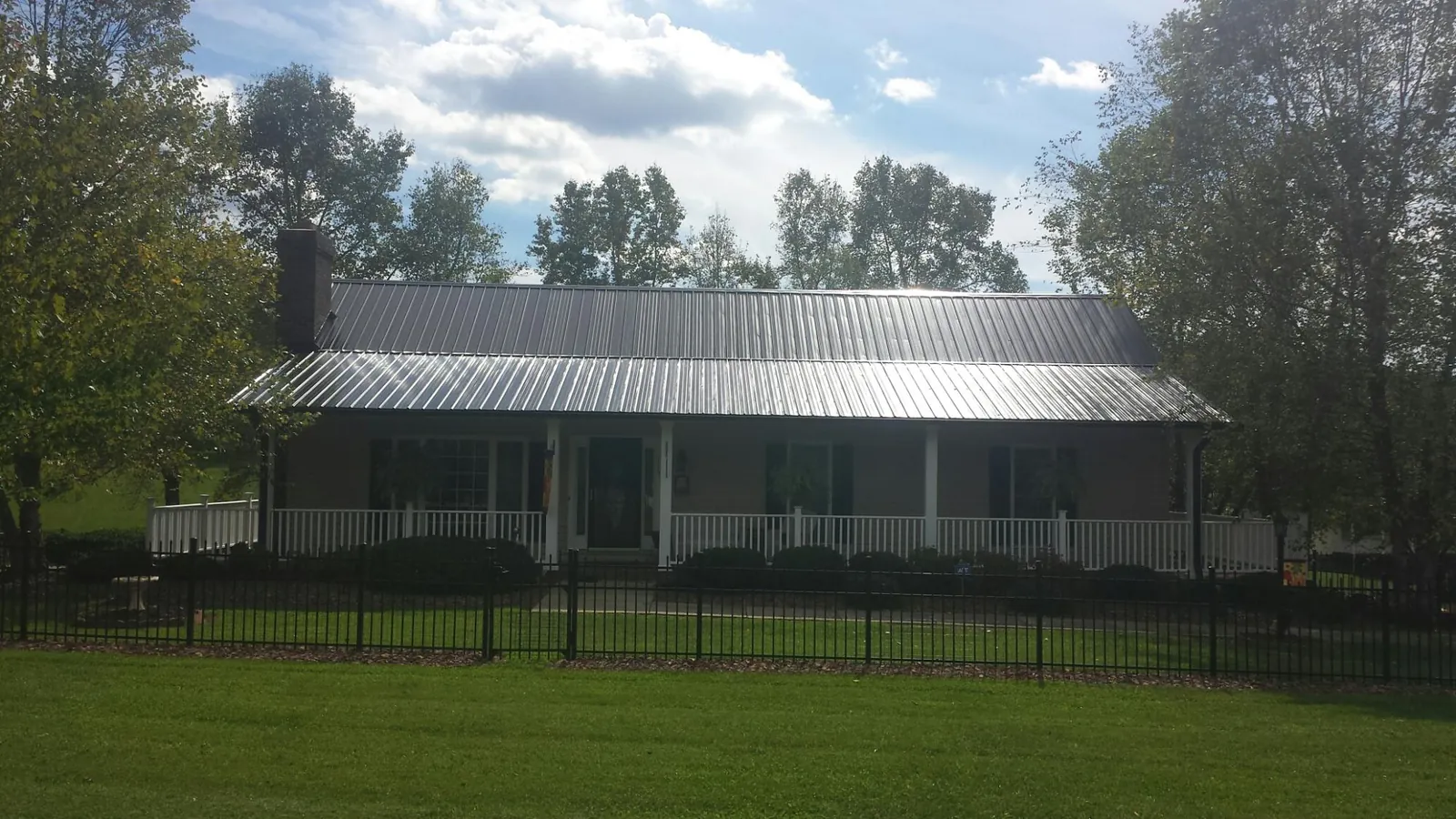 Gray metal roof on a brick ranch with a full width front porch — Gutter Guard Installation work by our crew in Orange